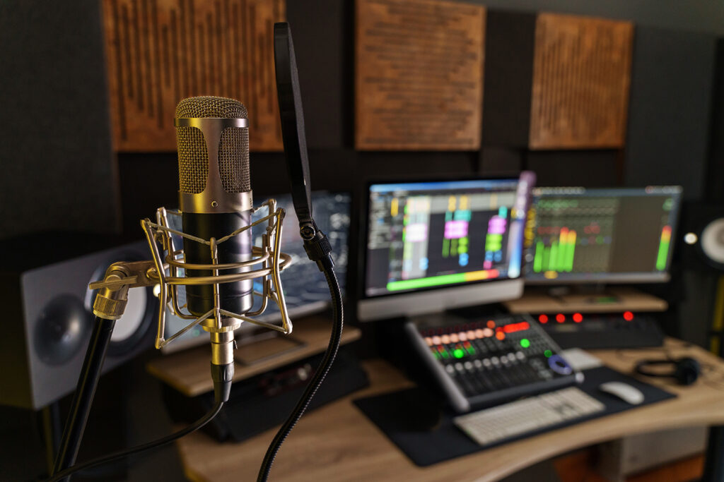 Professional microphone in a small music sound production studio workstation - digital equipment in the production studio room, with mixer, computers and speakers